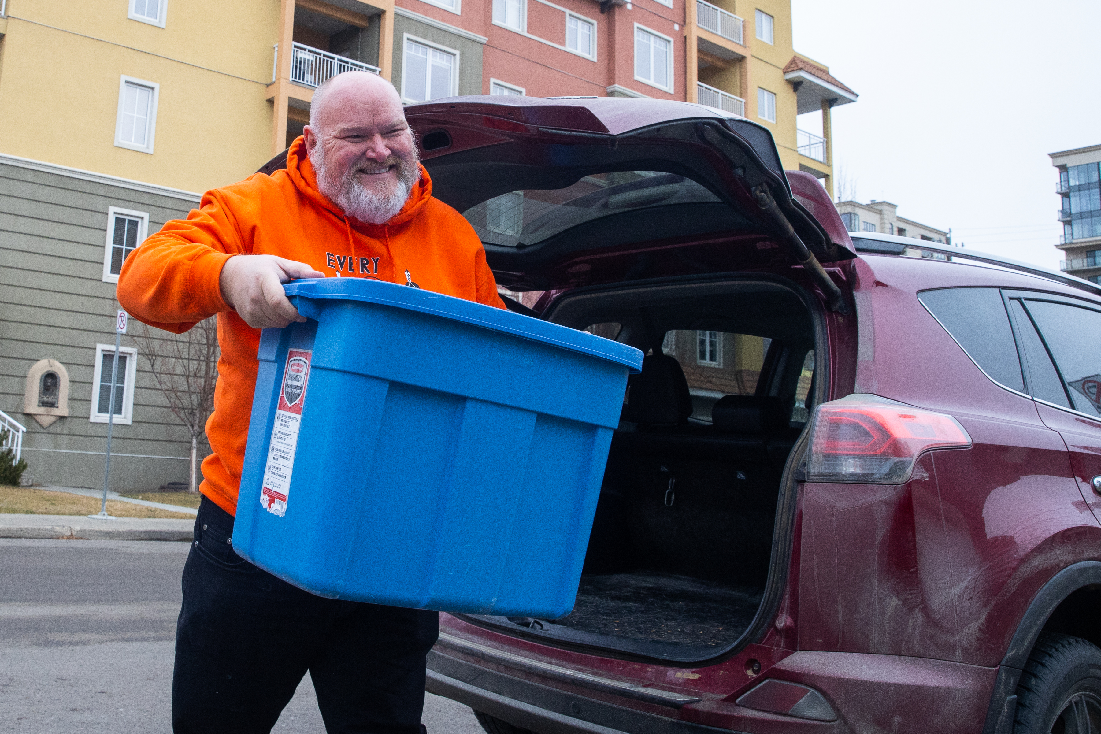 Man carries bin of food. 