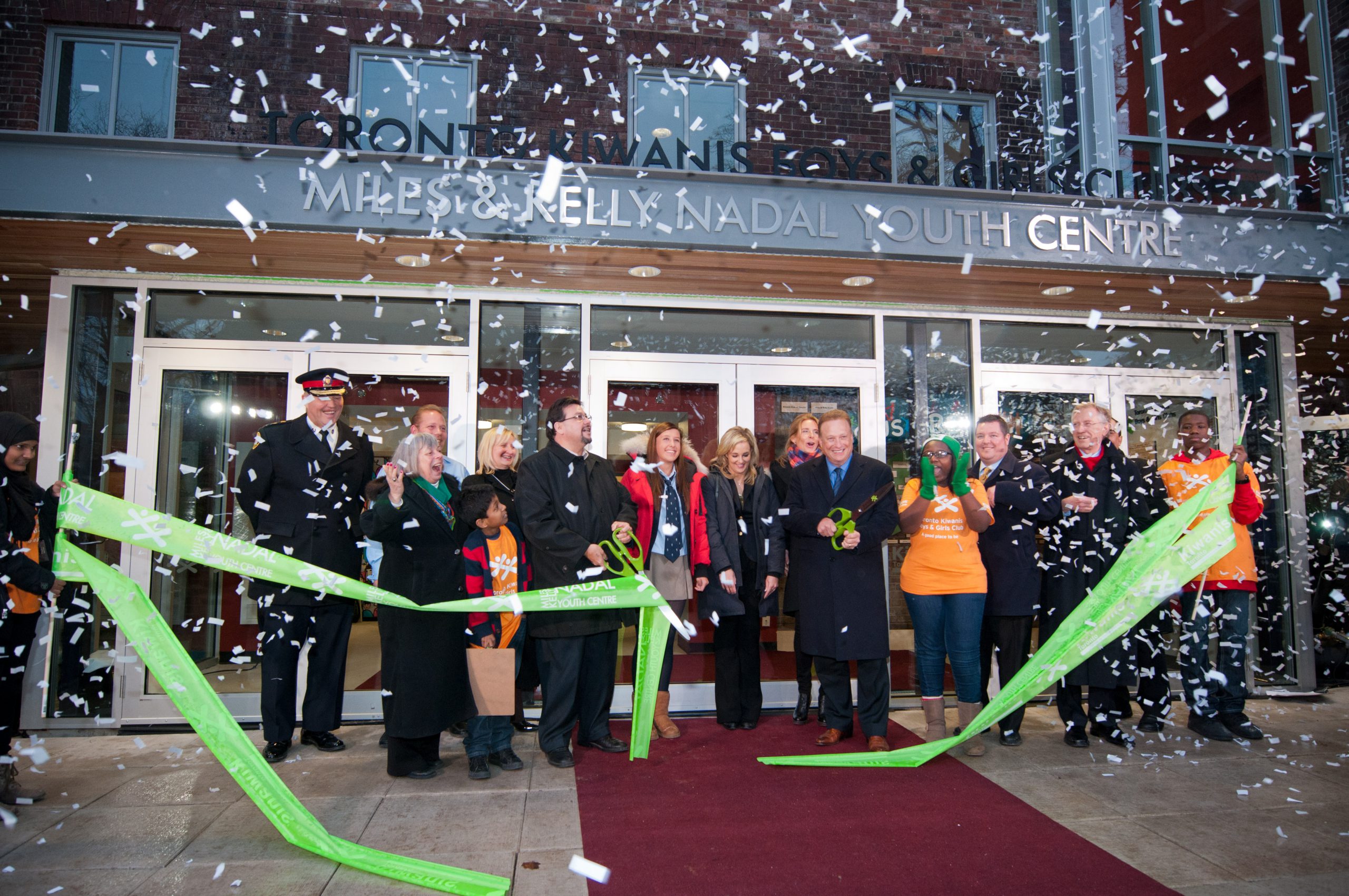 Chris Dunlop, local politicians and representatives from BGC Toronto Kiwanis applaud as a ceremonial ribbon is cut in front of the new building and confetti flies through the air