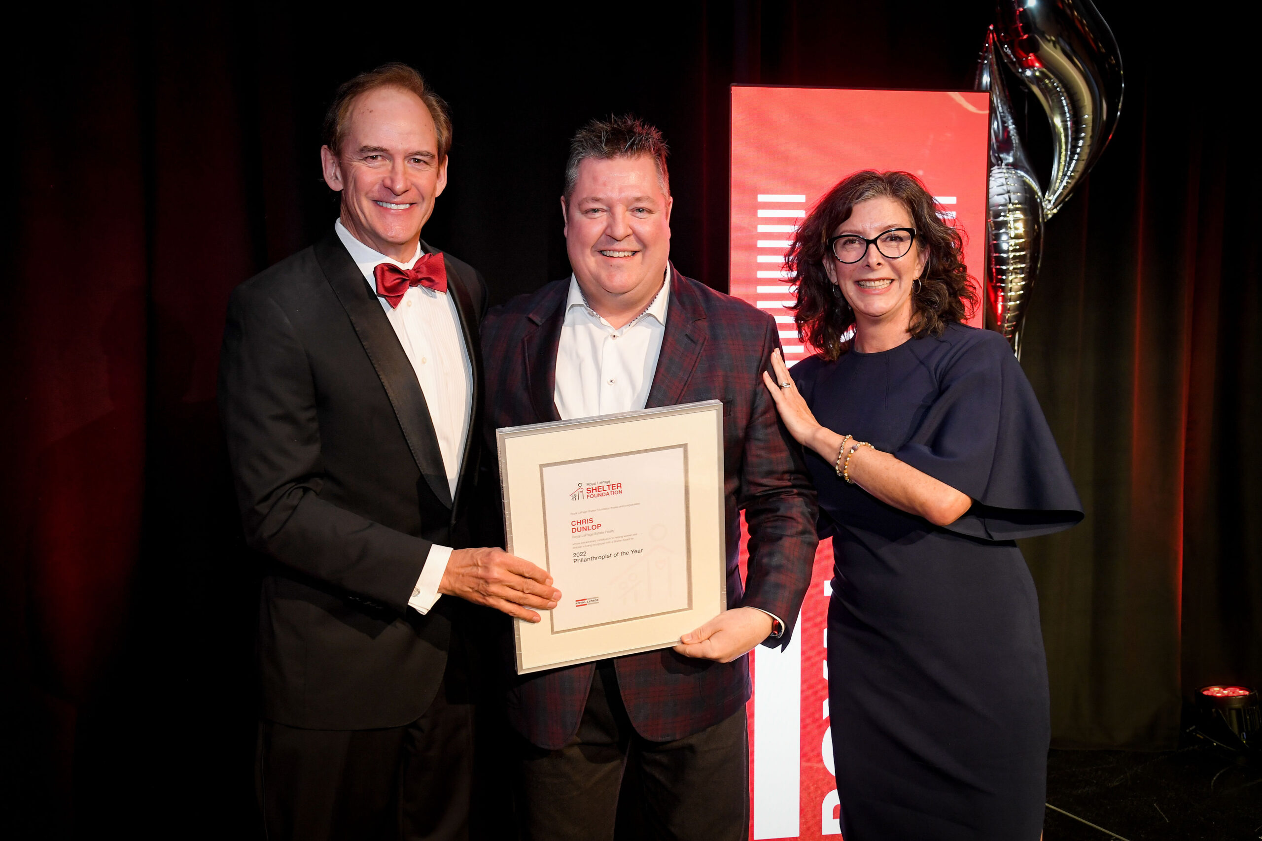 Chris stands smiling with representatives from the Royal LePage Shelter Foundation as he receives his award