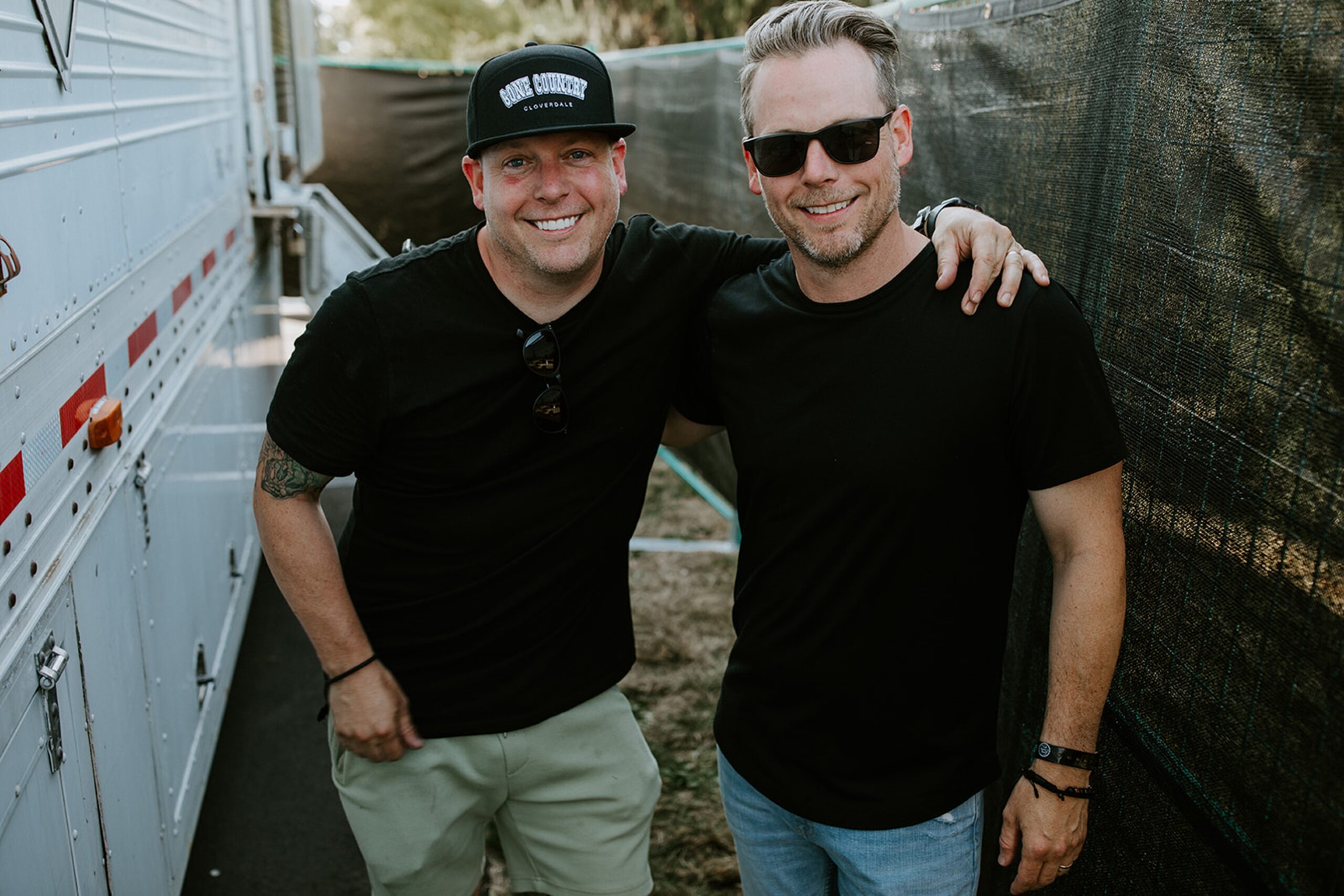 Les frères Chris et Jamie sourient, les bras enroulés autour des épaules de l'autre au concert Gone Country