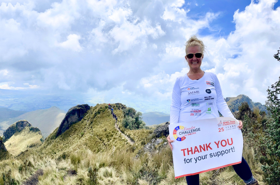 Lori stands on top of a mountain in Ecuador holding a thank you sign for all her Royal LePage Trek for Shelter challenge donors.