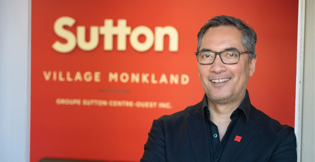 Erik Hamon stands smiling in front of his brokerage sign